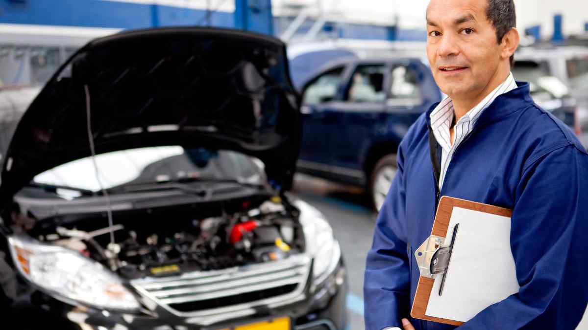 A mechanic next to a vehicle that he needs to inspect.